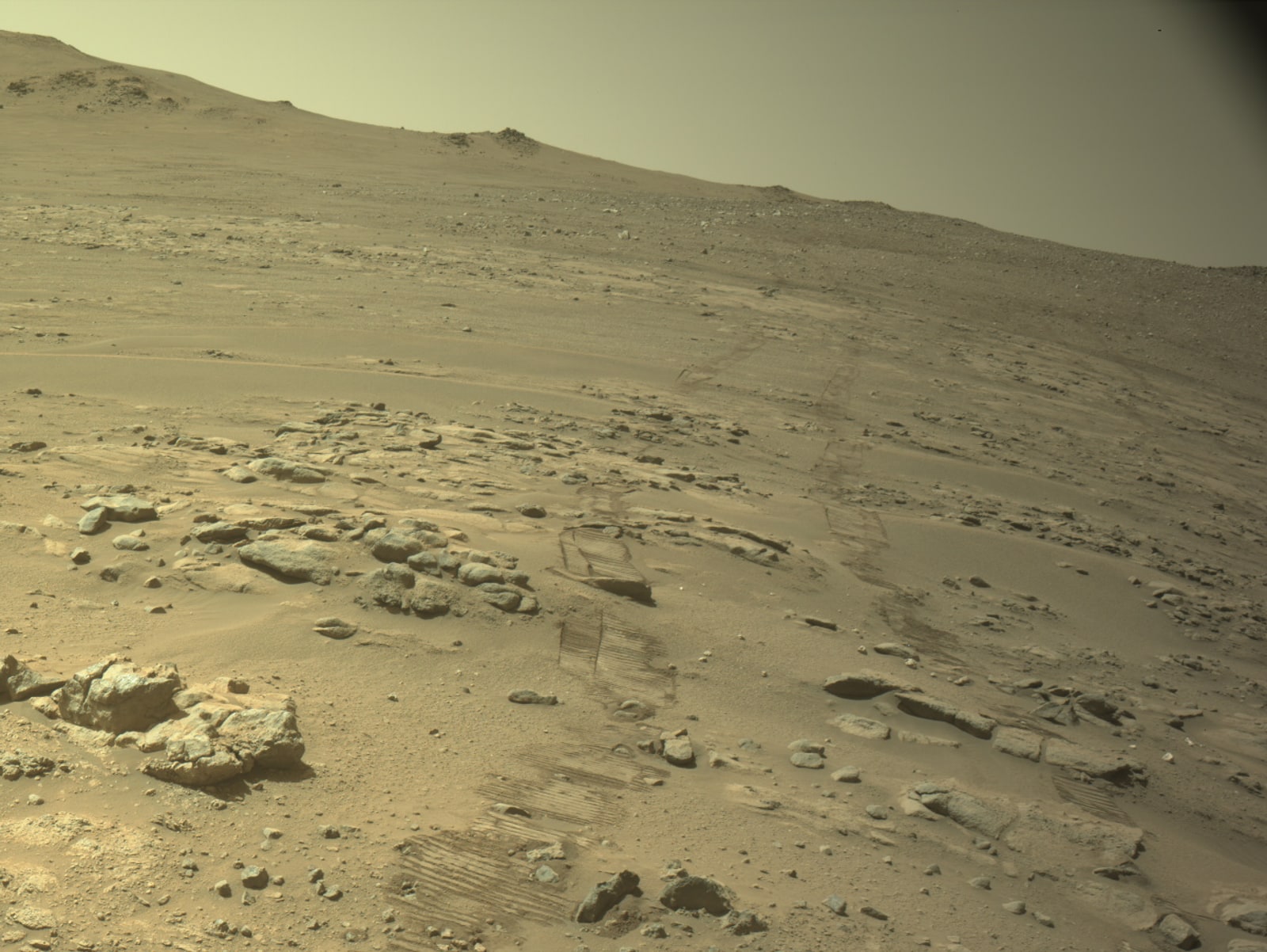 毅力號於 2026 年 10 月 11 日拍攝的火星地形,近處可見輪胎留下的車轍,周圍散布岩石與沙地。